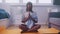 Meditation relaxation and wellbeing concept. Young african american black woman meditating in her appartment
