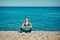 Meditation sitting on warm beach rocks. Stunning nature view and fresh air. Yoga time and healthy lifestyle concept