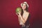 Meditative girl with pink make up, wearing jeans, hat and top, posing at red studio background, holding watermelon, emotionally