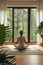 Meditative pose with a forest backdrop through large windows in a serene home environment.