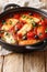 Mediterranean baked Halloumi with tomatoes, peppers, olives in a spicy sauce close-up in a pan. vertical