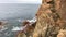 Mediterranean bay with brown and red cliffs and waves in the stormy blue water