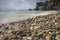 Mediterranean beach at slow motion speed long exposure - colorful pebbles and silky waves of blue sea on the shore. Texture