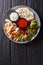 Mediterranean Chicken Shawarma Bowl with hummus, vegetables salad and sauce close-up. Vertical top view