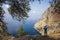 Mediterranean coast in Turkey, Man standing on cliff under big olive tree and taking photo of outstanding view of Butterfly Valley
