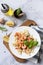 Mediterranean cuisine, seafood diet. Italian farfalle pasta with prawns garlic, basil and lemon on a marble tabletop. Top view