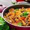 Mediterranean eggplant pasta in pot with tomatoes, red pepper and parsley on grey background.