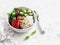 Mediterranean quinoa bowl with avocado, cucumbers, olives, roasted pepper, feta cheese, arugula. On a white background