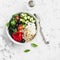 Mediterranean quinoa bowl with avocado, cucumbers, olives, roasted pepper, feta cheese, arugula. On a white background.