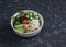 Mediterranean quinoa bowl with avocado, cucumbers, olives, tomatoes, feta cheese, arugula. On a dark background.