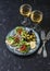 Mediterranean style antipasto and wine. Smoked salmon, avocado, arugula bruschetta, olives and two glasses of white wine