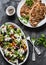 Mediterranean style lunch table - Greek chickpeas salad and pork chops on dark background, top view