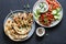Mediterranean style lunch table - turkey skewers, flatbread, tomatoes, cucumber salad, baked sweet pepper, yogurt herb sauce  on a