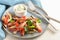 Mediterranean vegetables from the oven with parsley and dip on a blue plate, white wooden table and cutlery, healthy diet meal