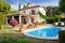 mediterrean house exterior with well-maintained garden, patio furniture, and swimming pool