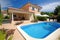 mediterrean house exterior with well-maintained garden, patio furniture, and swimming pool