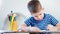 Medium close-up diligent concentrated little child boy drawing picture using blue marker