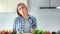 Medium close-up portrait of charming woman eating tasty fresh vegetables looking at camera