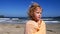 Medium closeup cute child with blonde curly hair feeling cold on beach warming wrapped in towel