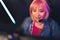 Medium closeup of pretty Asian female player in headphones and pink wig copy space concept