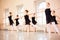 Medium group of teenage girls in black dresses practicing ballet moves in a large dance studio