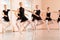 Medium group of teenage girls practicing ballet moves in a large dancing studio