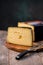 Medium hard cheese head gouda edam on wooden board with knife wooden texture daylight