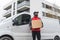 Medium long outdoor shot of tall focused Black deliveryman carrying a big parcel packed in cardboard box standing in