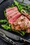 Medium rare sliced grilled striploin beef steak or new york steak. Black background. Top view