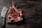 Medium rare Tomahawk meat marbled dry aged beef grilled, on wooden serving board, on old dark  wooden table background, with copy