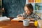 Medium shot of adorable pupil child school girl doing homework writing in notebook sitting at table with paper book.