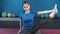 Medium shot Asian smiling fitness woman doing stretching raising legs making pilates exercise
