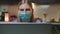 Medium shot of computer monitor and woman in medical mask reading something on it