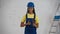 Medium shot of a dark-skinned young female construction worker standing in the room under renovation, holding