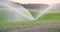 medium shot of grass sprinkler splashes water over the lawn