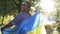 Medium shot happy African American plus-size woman spinning with Ukrainian flag in sunrays smiling. Portrait of cheerful