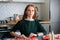 Medium shot portrait of attractive young woman gluing envelopes on board with gifts for children making Christmas advent