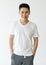 Medium shot portrait of a casual Asian handsome man with cute smiling in a white v-neck short sleeve t-shirt and gray pants with