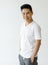 Medium shot portrait of a casual Asian handsome man with cute smiling in a white v-neck short sleeve t-shirt and gray pants with