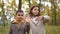 Medium shot portrait of cute boy and girl waving in slow motion looking away standing outdoors. Smiling positive