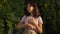 Medium shot portrait of happy intelligent Caucasian teenage girl standing at golden sunset with books in park looking