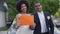 Medium shot portrait of happy joyful couple holding Just married sign looking at camera standing at car. Cheerful