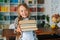 Medium shot portrait of joyful elementary child school girl holding stack of books in library at school, looking at