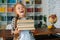 Medium shot portrait of laughing elementary child school girl holding stack of books in library at school, looking at