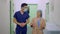Medium shot portrait of male plastic surgeon in face mask and female patient walking in slow motion along clinic
