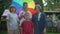 Medium shot positive Caucasian boys and girl looking at camera smiling spinning colorful umbrella standing outdoors