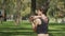Medium shot of a pretty woman stretching her shoulders at a busy park