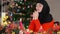 Medium shot religious young woman in hijab praying sitting at dinner table on Christmas eve at home. Portrait of