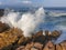 Medium shot of sea spray from sea crashing over rocks