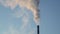 Medium shot of a smoke stack with a thick smoke plume. Beautiful blue sky.